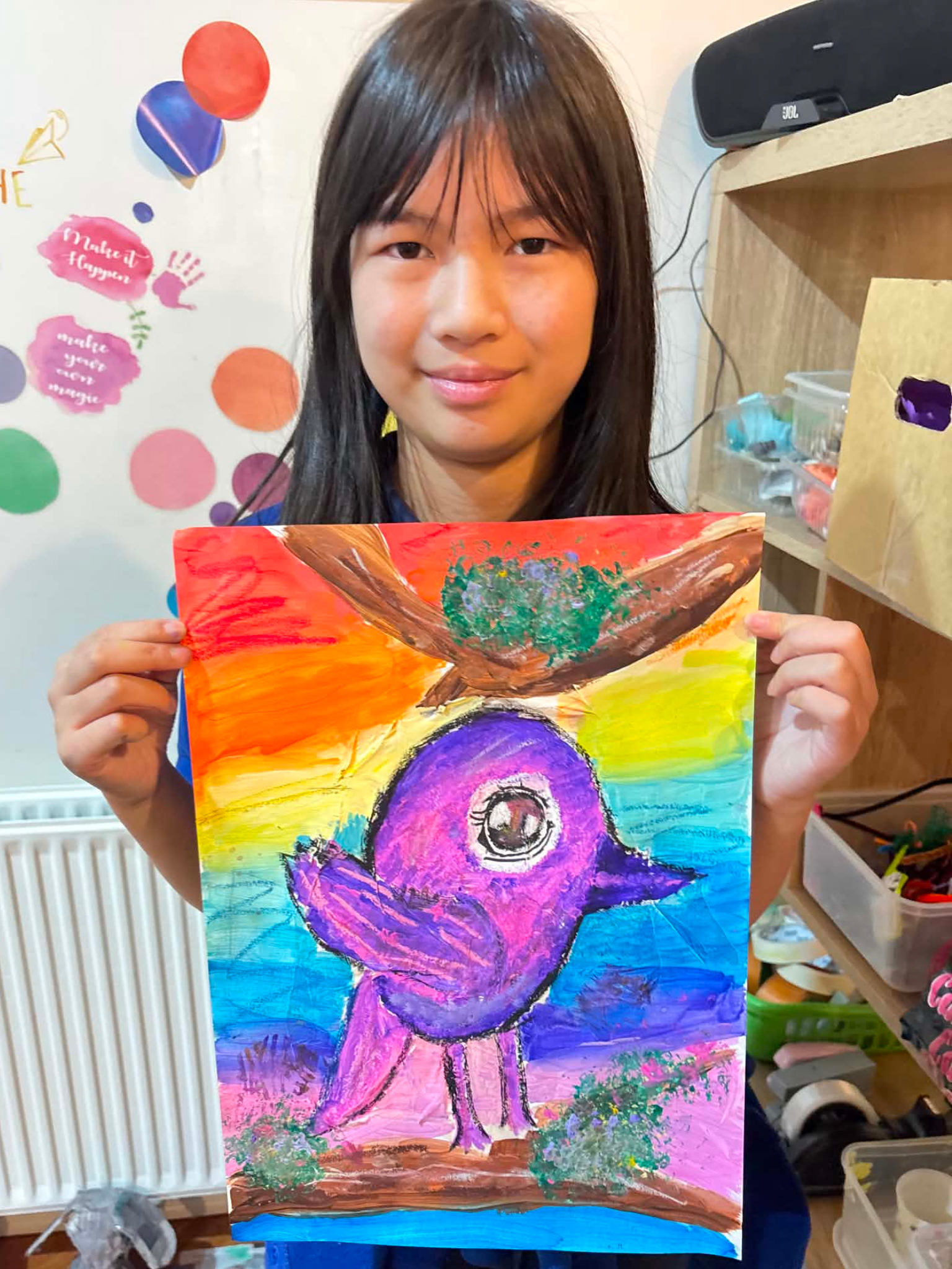A student from Wild at Art KIDS showcasing her bird painting artwork.